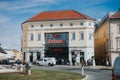 White car is parked in front of the entrance of the city Arkaden with people walking on the sidewalk