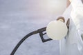 White car stopping and refueling with black fuel nozzle on a petrol station. Close-up, no people