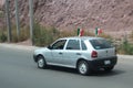 White car with two Mexican flags on the road