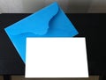 White card in a blue envelope on a black table for mocap, copy space