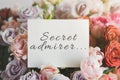 White card for a bouquet with the inscription secret admirer in a bright beautiful bouquet of roses Royalty Free Stock Photo