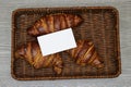 white card business above Fresh croissants in esparto halfah basket.