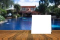 White card put on wood table and beautiful view of swiming pool at resort in background. product display template.
