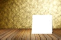 White card put on wooden desk or wooden floor on blurred abstract gold wall texture background.use for present or mock up