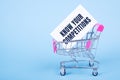 A white card with text KNOW YOUR COMPETITIONS stands in a shopping trolley on blue background Royalty Free Stock Photo