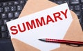 White card with the text SUMMARY in a craft envelope on a work desk with a modern laptop keyboard and burgundy pen. Flat layout of Royalty Free Stock Photo