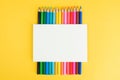 White cardboard poster on colored pencils on yellow background Royalty Free Stock Photo