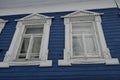 White carved architraves on the Windows of a blue wooden house