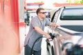 White caucasian car owner looks vacant while filling high energy power fuel into auto car tank in petrol station