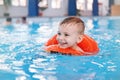 White Caucasian child in swimming pool. Preschool boy training to float with red circle ring in water Royalty Free Stock Photo