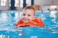 White Caucasian child in swimming pool. Preschool boy training to float with red circle ring in water Royalty Free Stock Photo