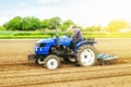 A white caucasian farmer on a tractor making ridges and mounds rows on a farm field. Preparing the land for planting future crop