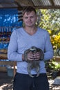 White male tourist holding a young sloth in his hands onboard a boat in on the Amazon River in Brazil, South America