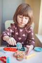 White Caucasian preschooler girl playing plasticine playdough indoors at home