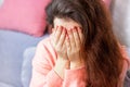 White Caucasian upset, worried and depressed brunette woman covering face with hands. Loneliness, sadness and grief concept.