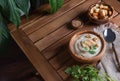 White cauliflower cream soup with croutons , spoon and herbs on brown table