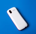 White cell phone on blue background. rear view. Royalty Free Stock Photo