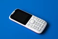 White cell phone with buttons on blue background. Royalty Free Stock Photo