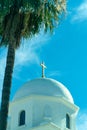 White cement church dome with dramatic lighting and front yard palm tree in whispy cloud blue sky background Royalty Free Stock Photo