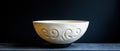 A white ceramic bowl with a black base and intricate scroll design sits on a dark surface. Royalty Free Stock Photo