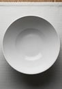A white ceramic bowl is centered on a plain, textured white placemat. The Royalty Free Stock Photo