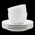 White Ceramic Bowls Stacked on a Stack of Four White Plates Against a White Backdrop Royalty Free Stock Photo