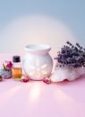 White ceramic candle aroma oil lamp with essential oil bottle and dried flowers, crystal geodes on modern pastel pink and blue bac Royalty Free Stock Photo