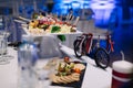 A white ceramic coaster with hors d`oeuvres on the wedding table.