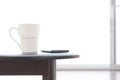 White ceramic coffee cup and smart phone on oval wooden table with blurred frosted glass sliding door in living room Royalty Free Stock Photo