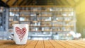 A white ceramic coffee mug with a red heart pattern on a wooden table. Blurred cafe background Royalty Free Stock Photo