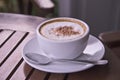 White ceramic cup of coffee and small dish on brown floor Royalty Free Stock Photo