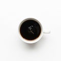 A white ceramic cup filled with dark black coffee sits on a plain white Royalty Free Stock Photo