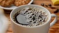 White ceramic cup with freshly brewed aromatic coffee and foam bubbles. A cup with a coffee or tea drink stands on the