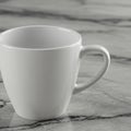White ceramic cup on a gray marble surface with subtle black veining. The cup has a Royalty Free Stock Photo