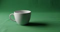 White ceramic cup with a handle placed on a green fabric surface. The background and Royalty Free Stock Photo