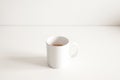 White ceramic cup of hot coffee with milk on a white wood table and refreshing look of the drink Royalty Free Stock Photo