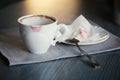 White ceramic cup with lipstick mark on table, gray linen napkin, saucer, spoon and crumpled paper napkin. Morning coffee. Mood of Royalty Free Stock Photo