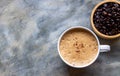 White ceramic cup of Mocha coffee on a concrete table near a wooden bowl of coffee beans. Selective focus of a cup of coffee