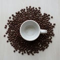 White ceramic cup positioned upside down, surrounded by coffee beans (Coffea) on a Royalty Free Stock Photo