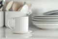 White ceramic cup with saucer placed on a kitchen counter surrounded by dishware in soft light Royalty Free Stock Photo