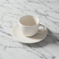 White ceramic cup and saucer set on a light gray marble surface with subtle veining. Royalty Free Stock Photo