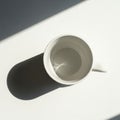 A white ceramic cup sits on a flat surface, casting a distinct o Royalty Free Stock Photo