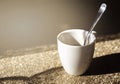 A white ceramic cup with a steel spoon filled with black coffee illuminated by natural sunlight Royalty Free Stock Photo