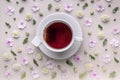 White ceramic cup with tea on a floral pattern on a beige background. Flower tea concept. Tea bag. Top view