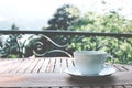 White ceramic cup of tea on a saucer on wooden table against picturesque background. Royalty Free Stock Photo