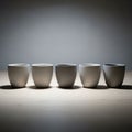 White ceramic cups are arranged in a straight line on a light wooden Royalty Free Stock Photo