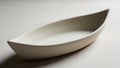 White ceramic dish shaped like a canoe placed on a smooth light colored surface Royalty Free Stock Photo