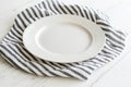 White ceramic empty plate on striped cloth on kitchen table Royalty Free Stock Photo