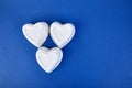 White ceramic hearts on blue trend color background. Flat lay composition. Romantic, St Valentines Day concept.