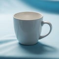 White ceramic mug with a curved handle, placed on a smooth light Royalty Free Stock Photo